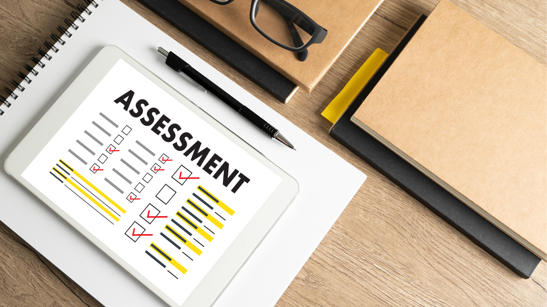 Na biurku leży kartka z napisem Assessment. Na niej lista z wykonanymi zadaniami.